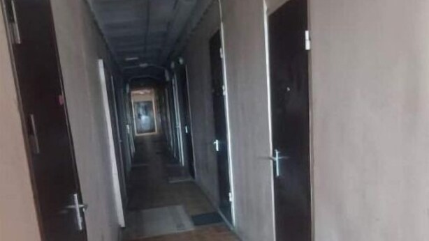 Un pasillo largo y estrecho con alfombra y puertas a ambos lados.