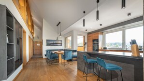 Une cuisine moderne avec des poutres en bois, un coin bar avec des tabourets et un espace repas avec une table et des chaises.