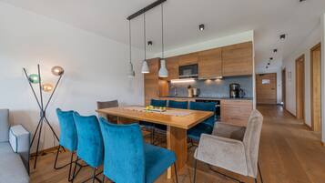 A modern kitchen with wooden cabinets, a central island, and a dining area with blue chairs.