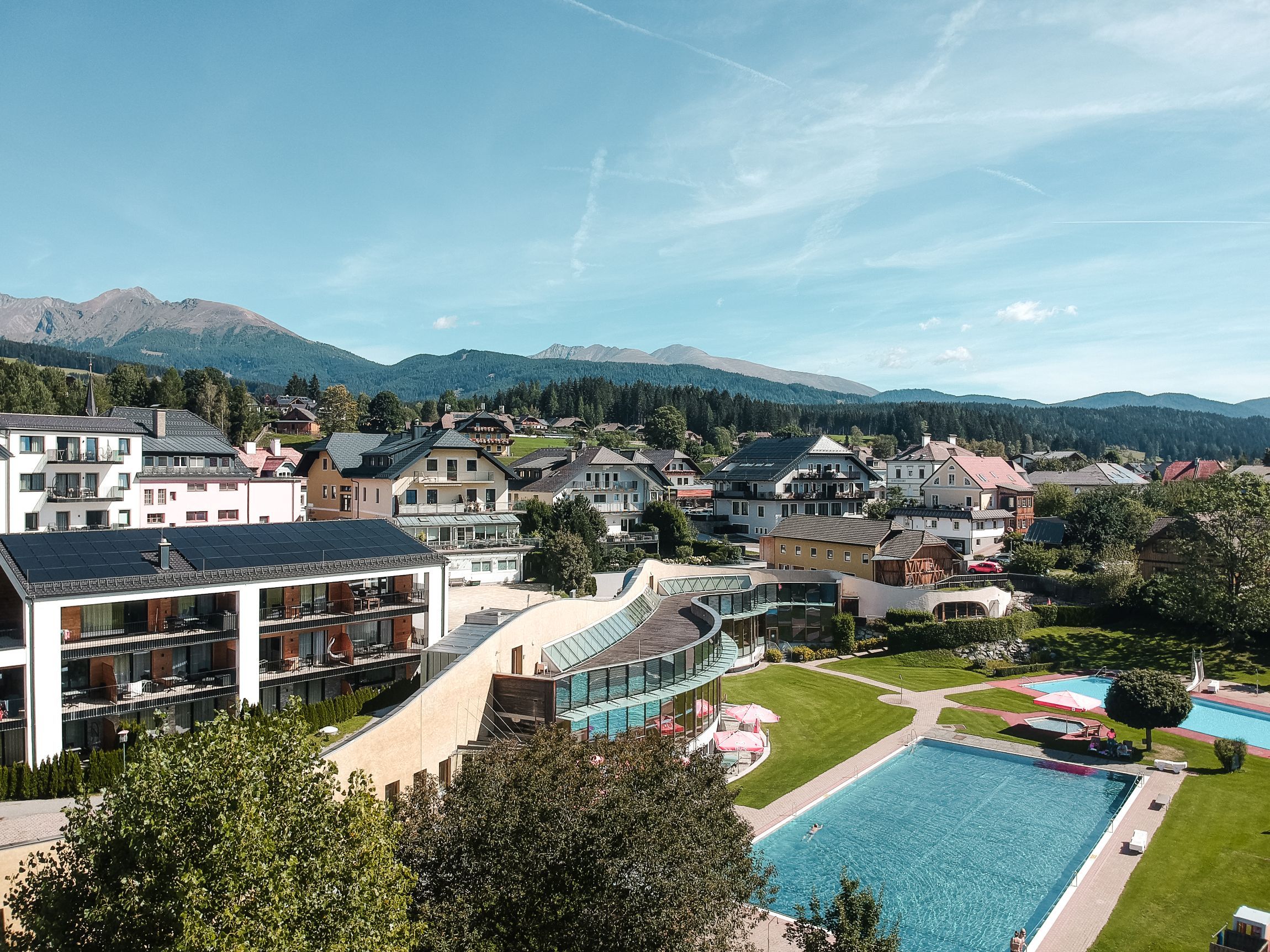 A residential area with a swimming pool, modern buildings, and a mountainous backdrop.