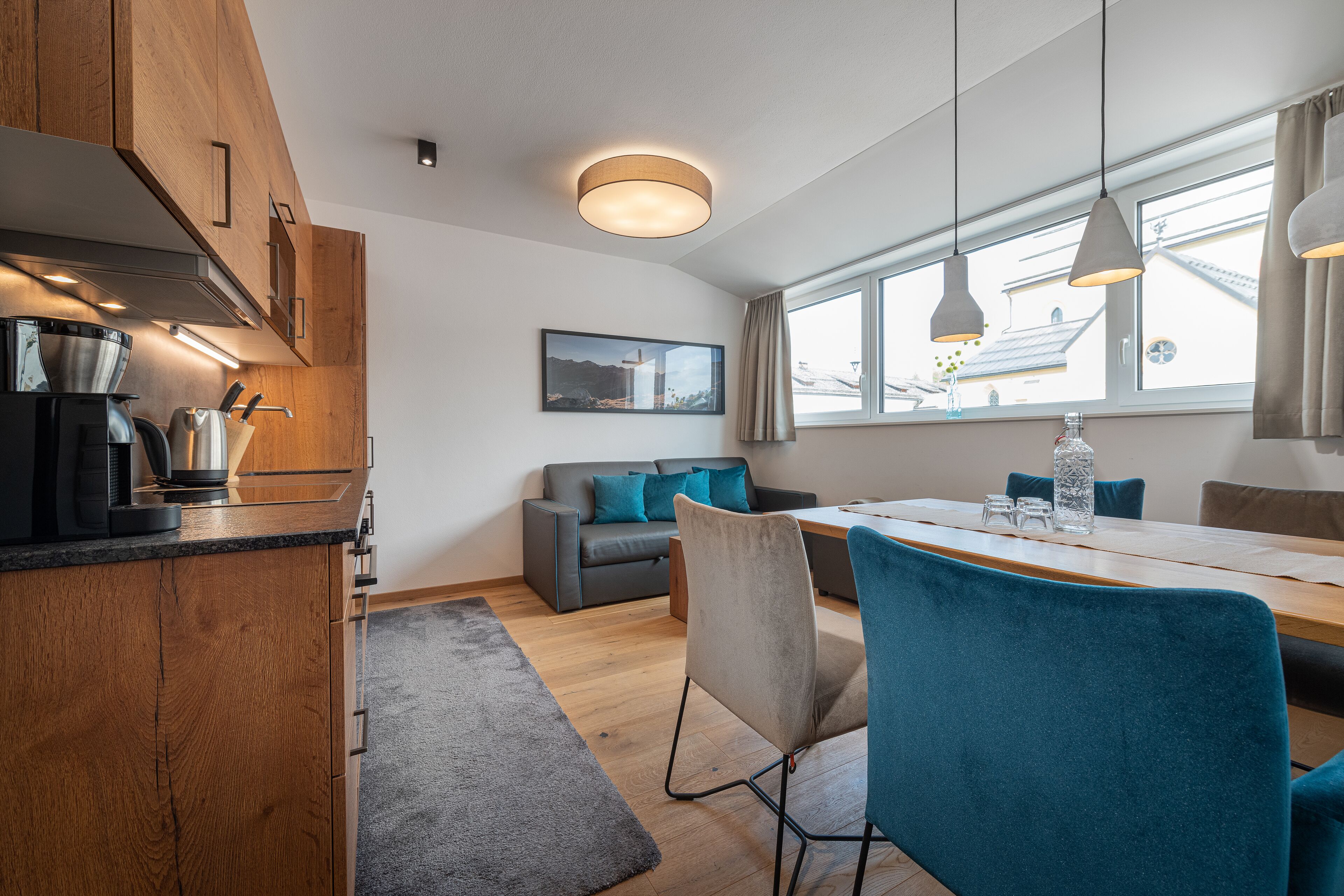 Une cuisine moderne avec des meubles en bois, un coin repas avec une table et des chaises, et un canapé avec des coussins.