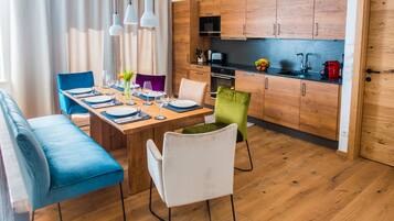 Une cuisine moderne avec des meubles en bois, un coin repas avec une table en bois dressée pour quatre personnes, et un canapé bleu.