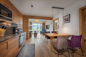 Una cuina moderna amb armaris de fusta, una zona de menjador amb taula i cadires, i vista a l'exterior.
