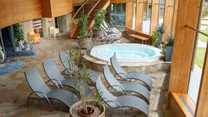 A spacious indoor area with a hot tub, lounge chairs, and potted plants. - AlpenParks Hotel & Apartment Carpe Solem (Mariapfarr)