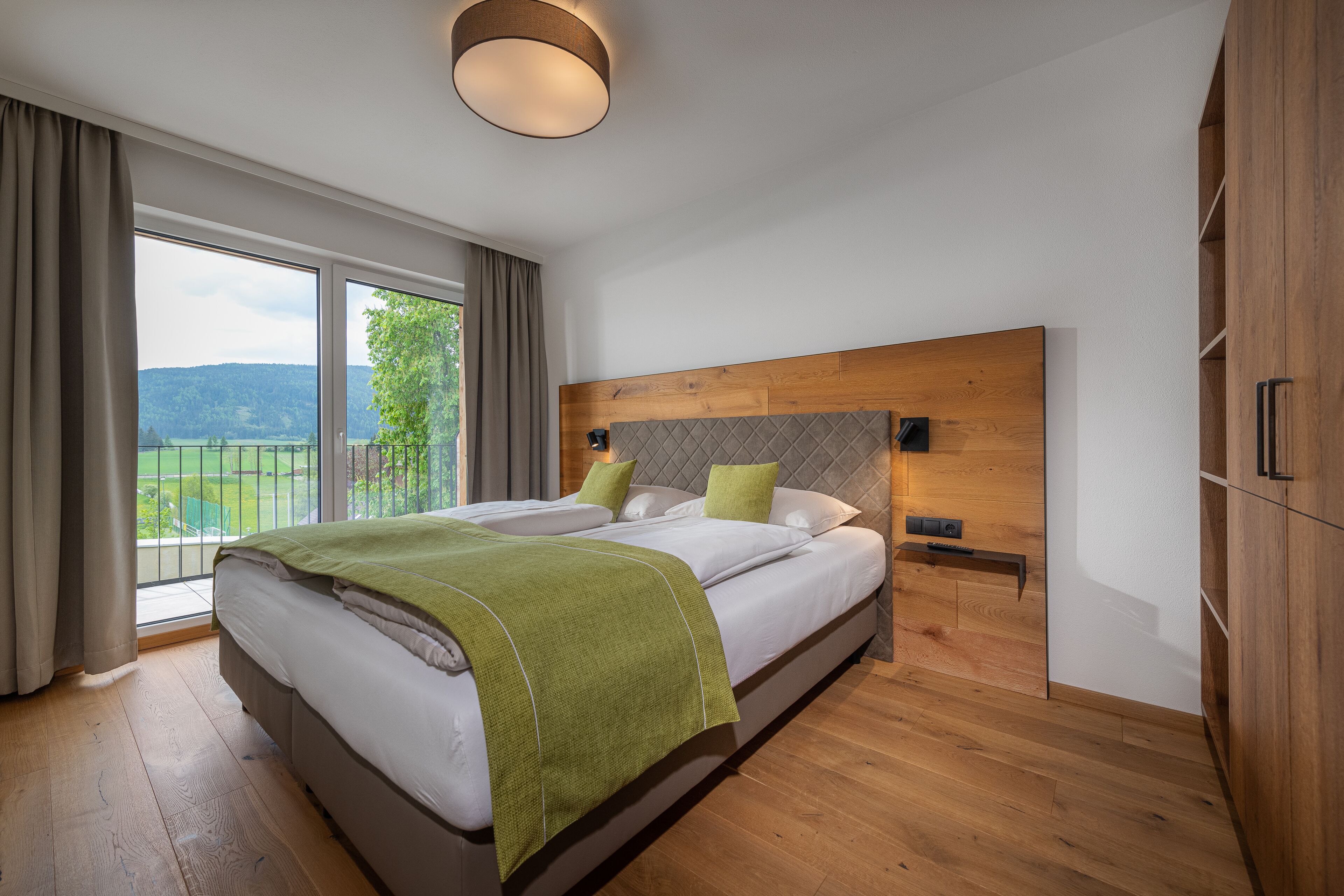 Un dormitorio moderno con una cama grande, cabecera de madera y vistas al exterior.