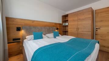 A bedroom with a bed, wooden headboard, nightstands, and a wardrobe.