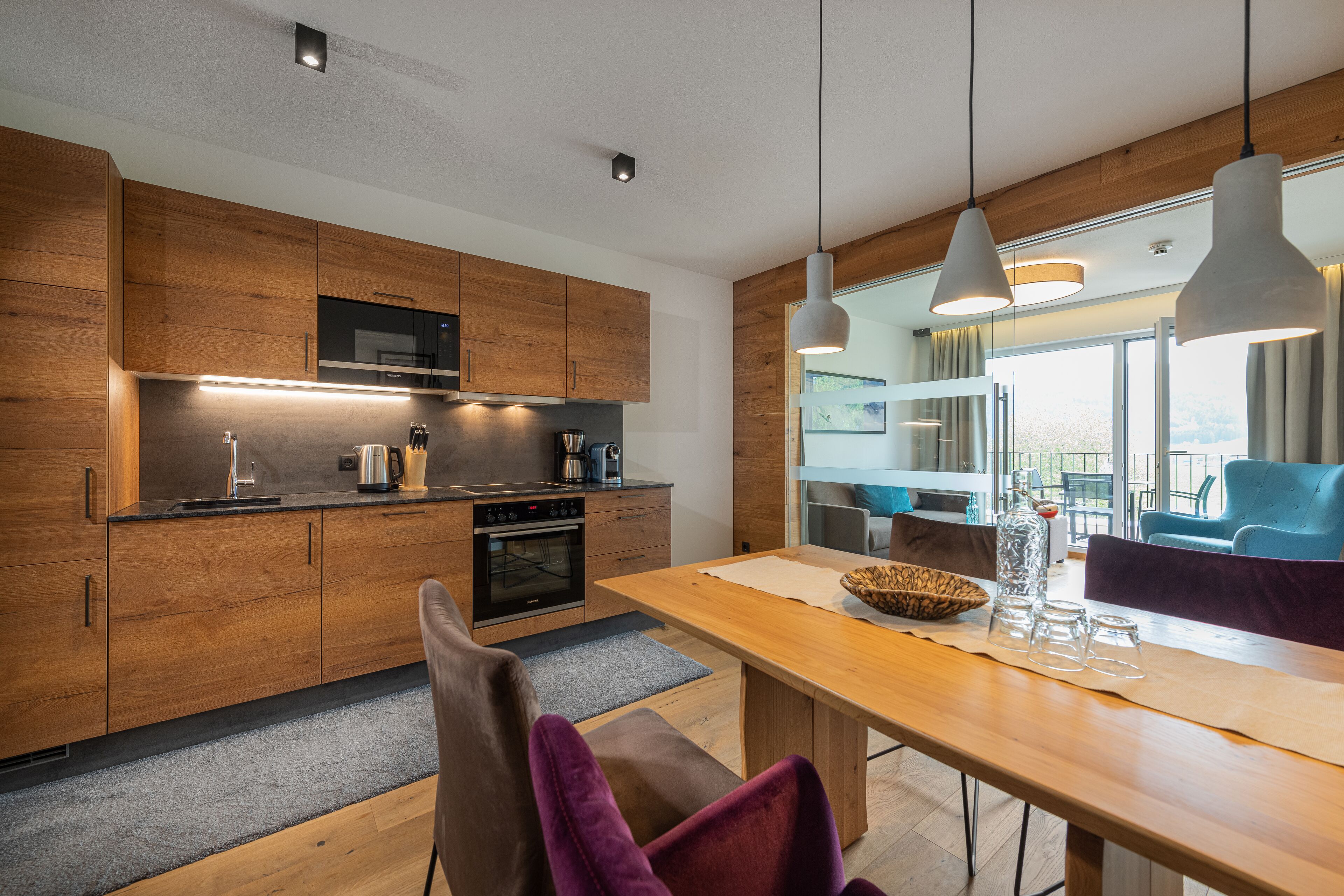 A modern kitchen with wooden cabinets, a built-in oven, and pendant lighting.