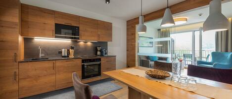 A modern kitchen with wooden cabinets, a built-in oven, and pendant lighting.