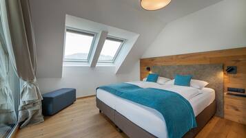 Une chambre à coucher moderne avec un grand lit, une lucarne, un banc et une tête de lit en bois.