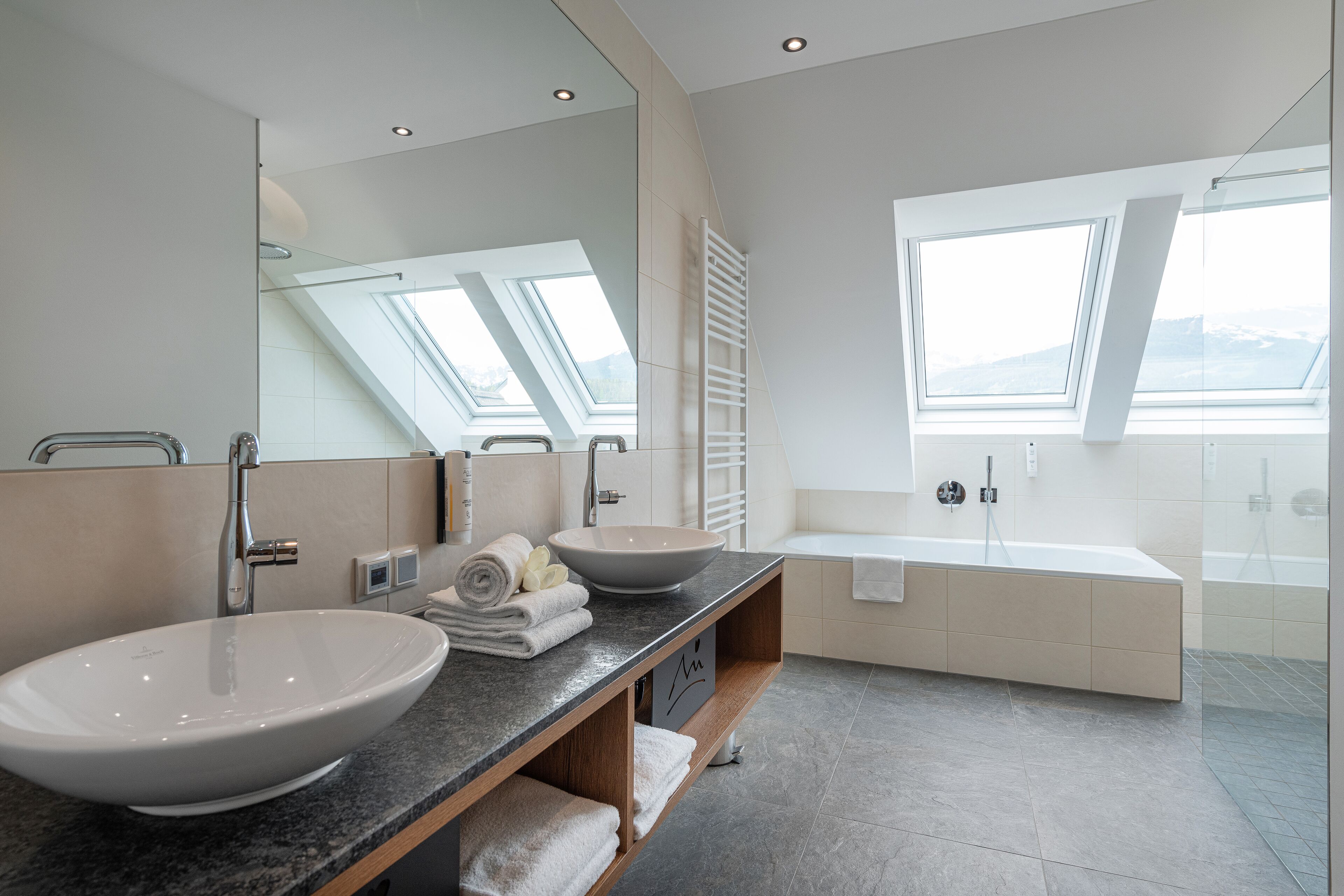 A modern bathroom with a large vessel sink, a freestanding bathtub, and skylights.