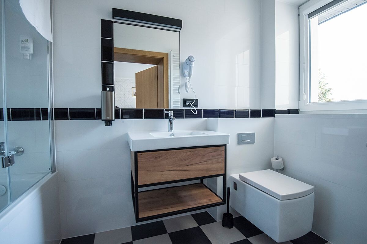 A modern bathroom with a white sink, a mirror, and a toilet.