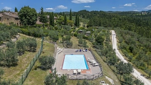 Ein Schwimmbecken, umgeben von einem eingezäunten Bereich, in der Nähe verläuft eine Straße.