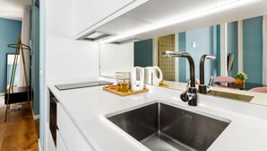 Eine moderne Küche mit einem großen Spülbecken, weißen Arbeitsplatten und einem Spiegel darüber.