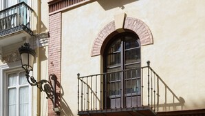 Un immeuble doté d’un balcon, d’une fenêtre surmontée d’un arc en briques et d’un lampadaire.