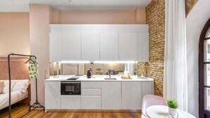 Una cocina compacta con armarios blancos, horno empotrado y una pequeña isla con fregadero.
