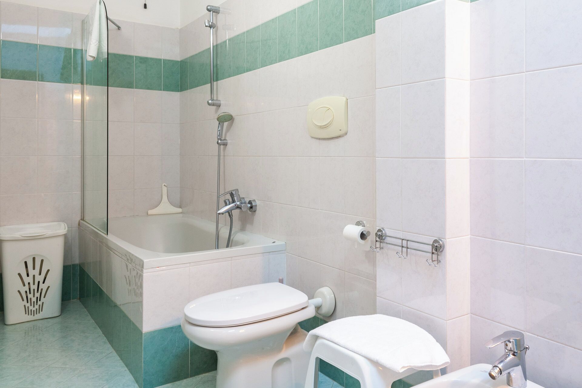 Een badkamer met een douchecabine van glas, een bad, toilet en wastafel.