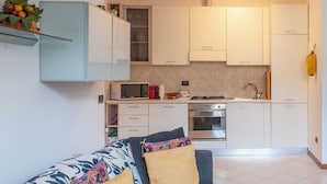 A compact kitchen with white cabinets, a microwave, a stove, and a sink. - BnButler - Asiago 41 (Milan)