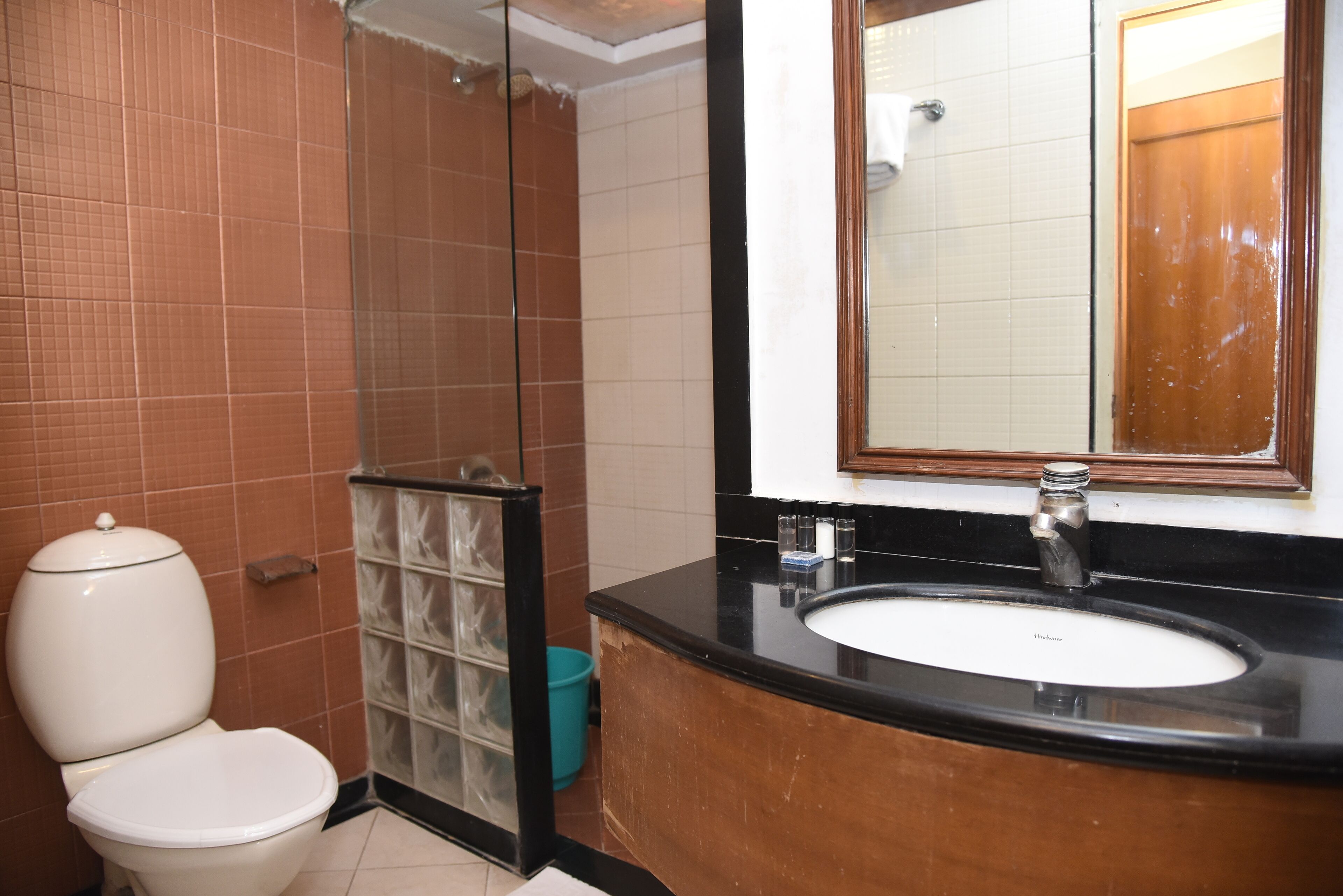 A bathroom with a toilet, sink, mirror, and shower.