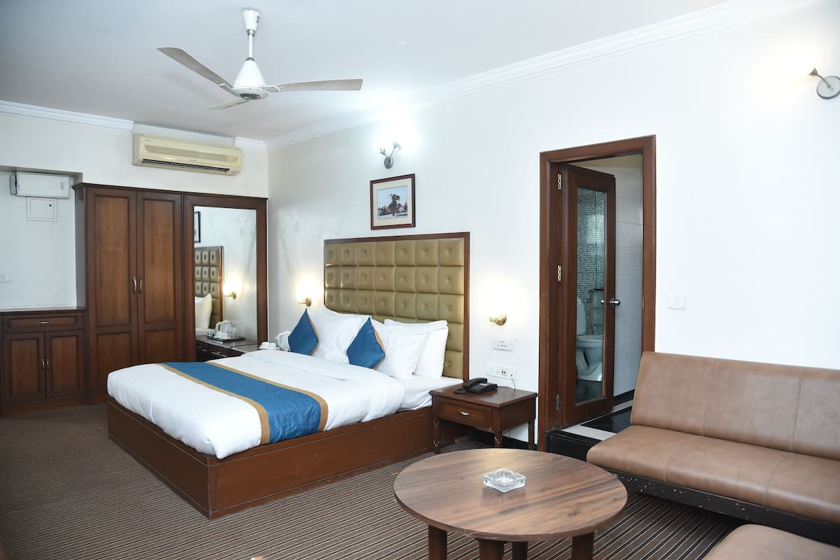 A hotel room with a bed, bedside table, nightstand, and a round coffee table.