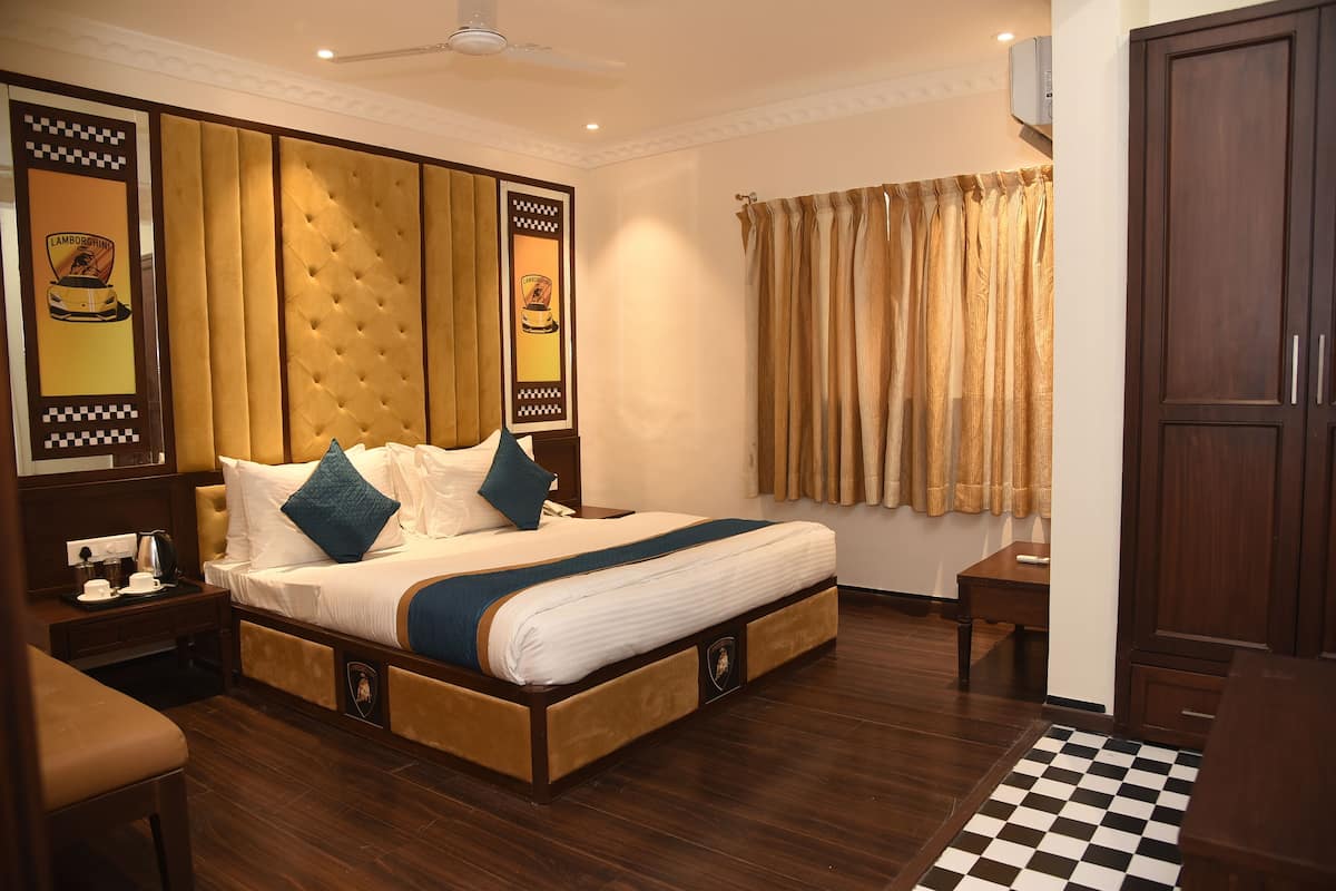A hotel room with a large bed, wooden headboard, a small bedside table, a desk, and a wardrobe.