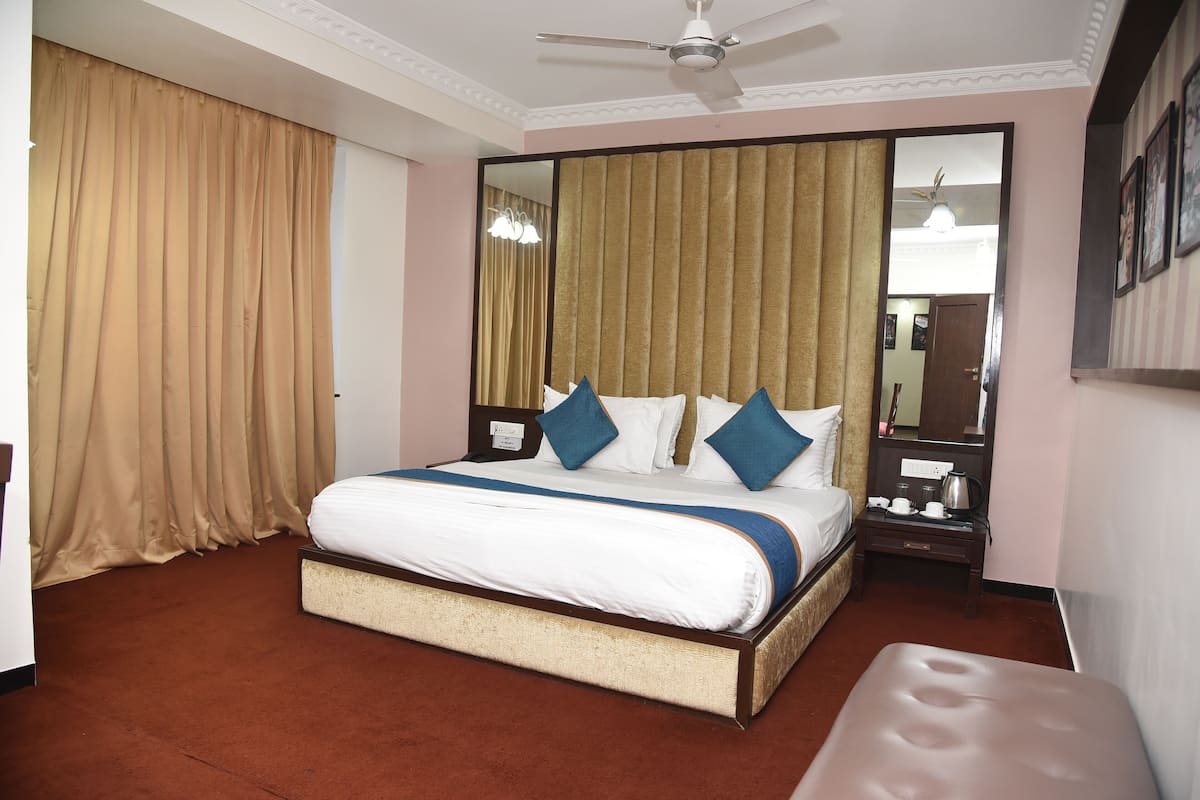 A hotel room with a large bed, a bedside table with a lamp, a mirror, and a ceiling fan.