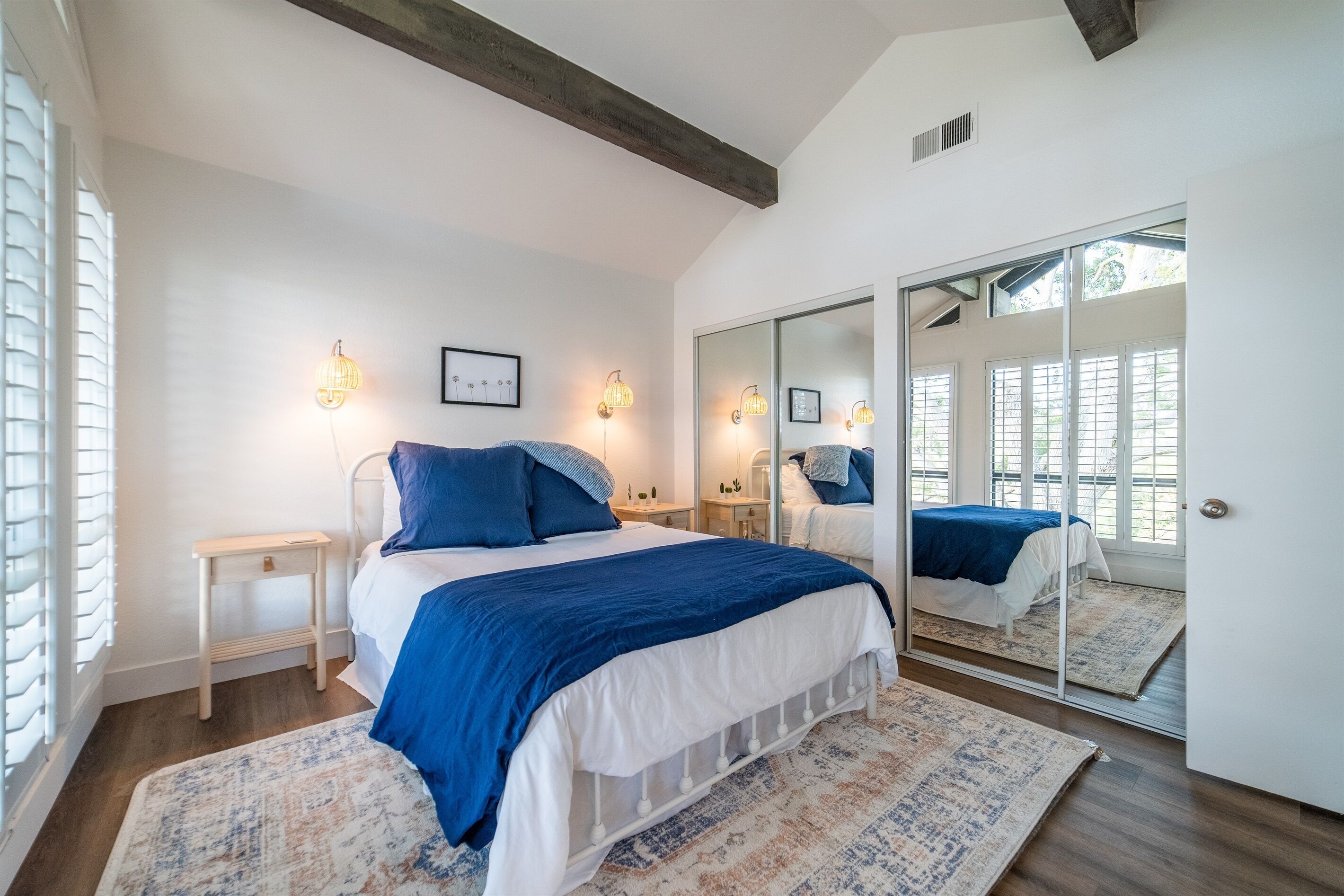 Une chambre à coucher avec un grand lit, des tables de chevet, un miroir et une armoire.