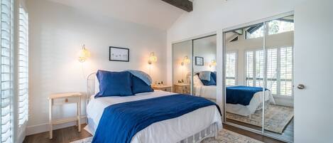 Une chambre à coucher avec un grand lit, des tables de chevet, un miroir et une armoire.