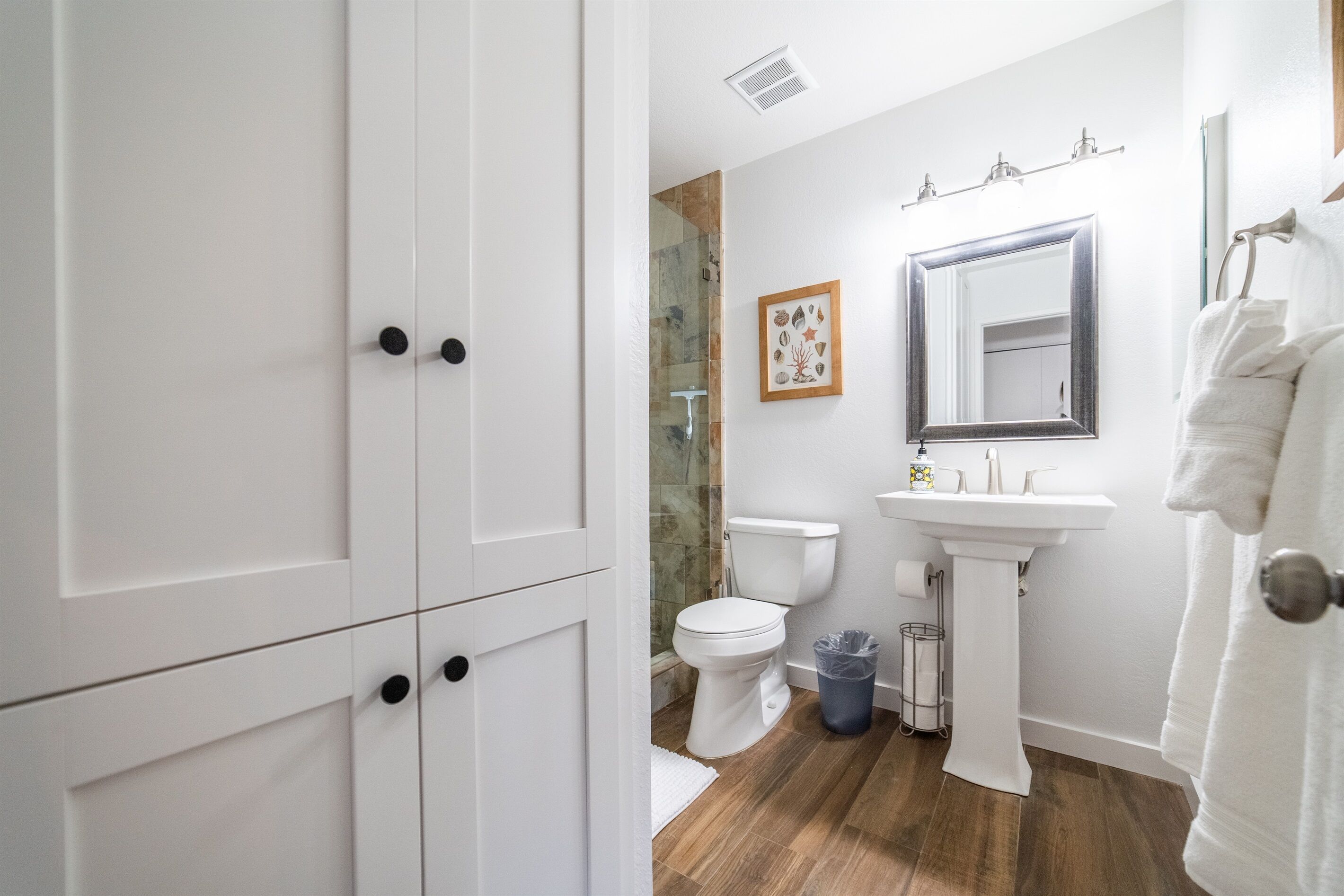 A bathroom with a toilet, sink, and mirror. There is a white towel hanging on the right side.