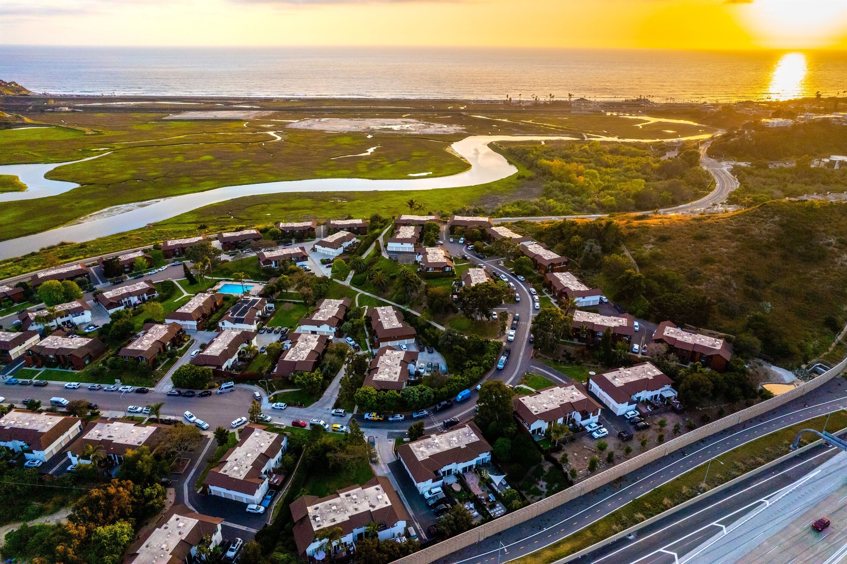 An aerial view of a residential area with houses, roads, and a body of water.