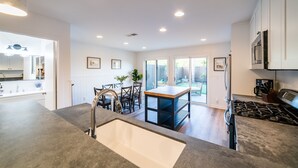 Une cuisine moderne dotée d’un îlot central, d’un coin repas avec des chaises et d’une vue sur l’extérieur.