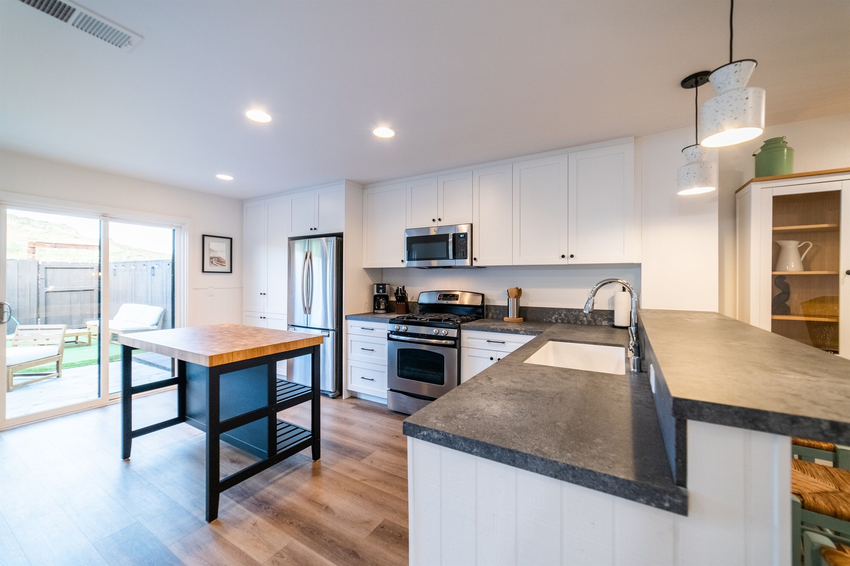 A modern kitchen with white cabinets, a stainless steel oven, a microwave, and a granite countertop.