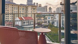 A high-rise hotel room with a large window overlooking a cityscape, including modern and traditional buildings. - Mercure ICON Singapore City Centre (Singapore)