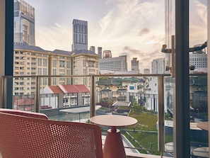 A high-rise hotel room with a large window overlooking a cityscape, including modern and traditional buildings. - Mercure ICON Singapore City Centre (Singapore)