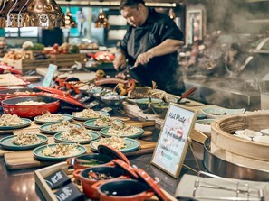 A buffet with various dishes and cooking equipment. - Mercure ICON Singapore City Centre (Singapore)