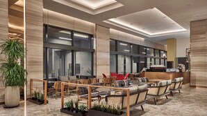 Un moderno vestíbulo de hotel con una recepción, una zona de estar y grandes ventanales.