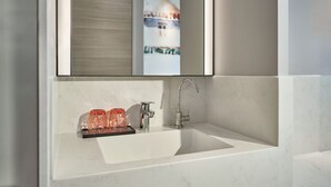 A bathroom with a white sink, a modern faucet, and a glass container. - Mercure ICON Singapore City Centre (Singapore)