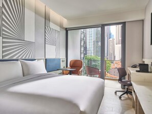 Un hotel moderno con una cama grande, un escritorio, una silla y vistas a la ciudad a través de amplias ventanas.