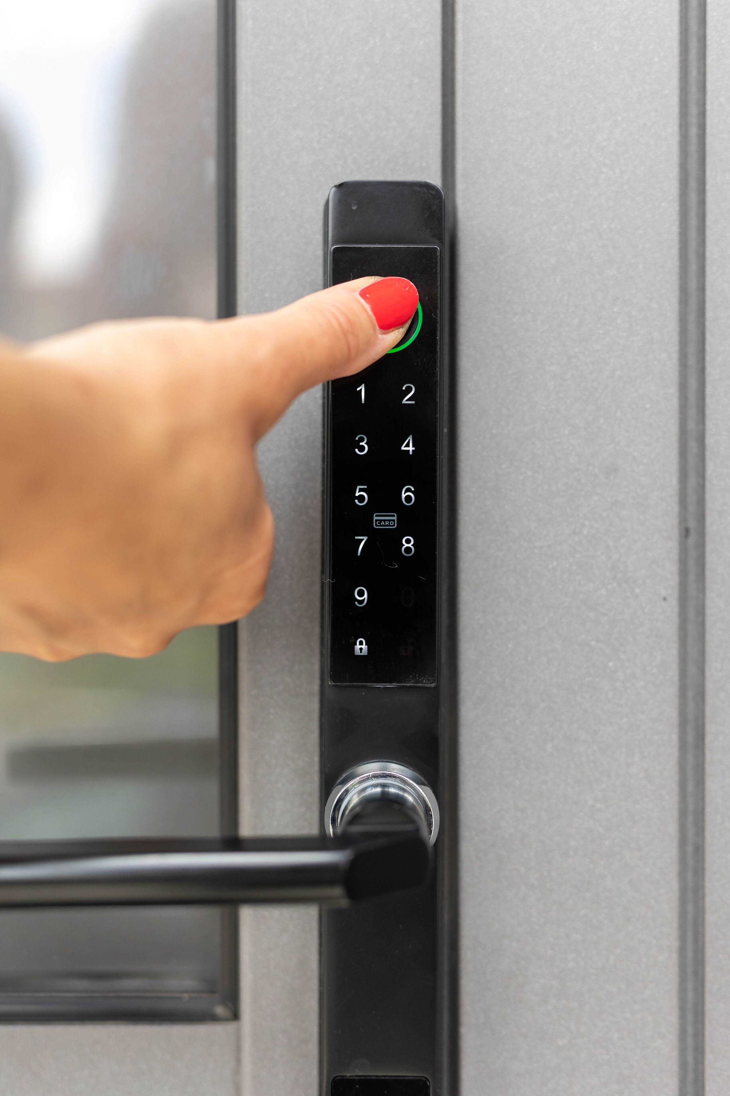A hand pressing a button on a numeric keypad door lock.