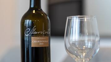 A bottle of Chardonnay 2020 and an empty wine glass on a marble surface.