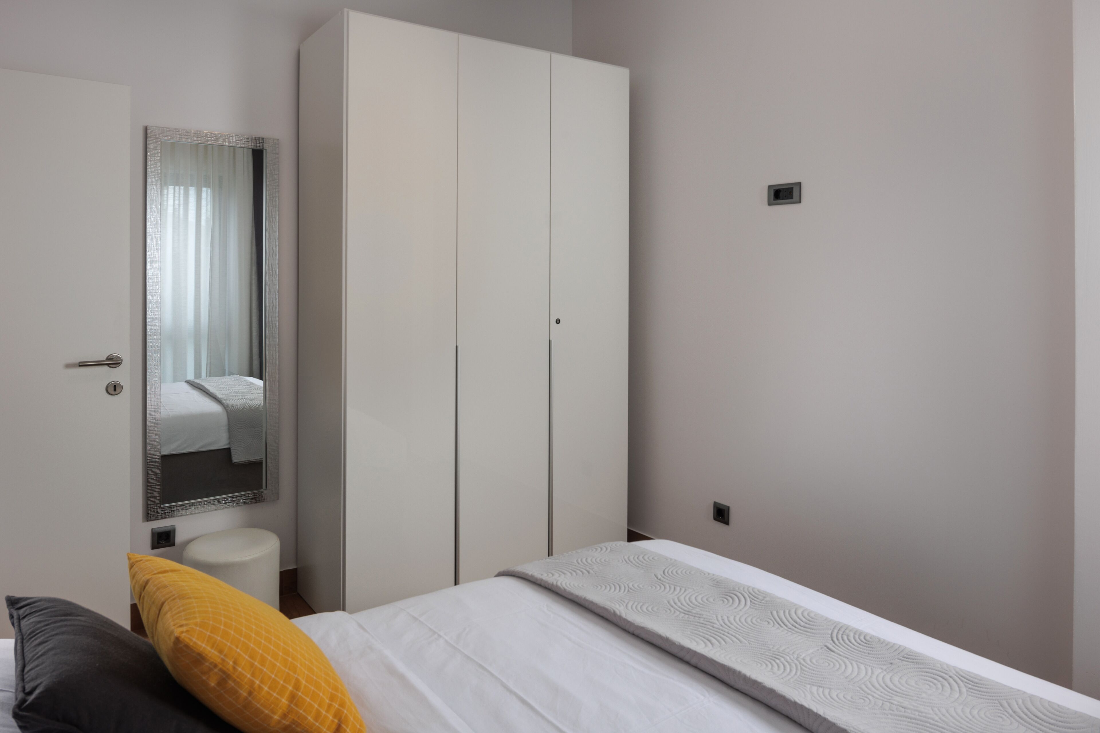 Un dormitorio con cama, armario, espejo y un inodoro.