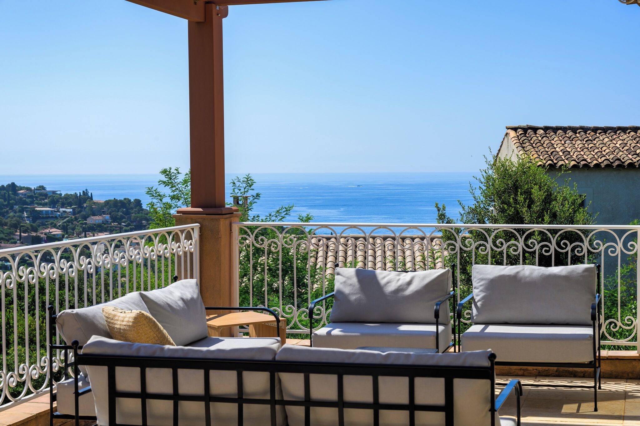 Un balcon avec vue sur la mer, aménagé avec deux canapés blancs et une petite table.