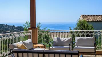 Un balcon avec vue sur la mer, aménagé avec deux canapés blancs et une petite table.