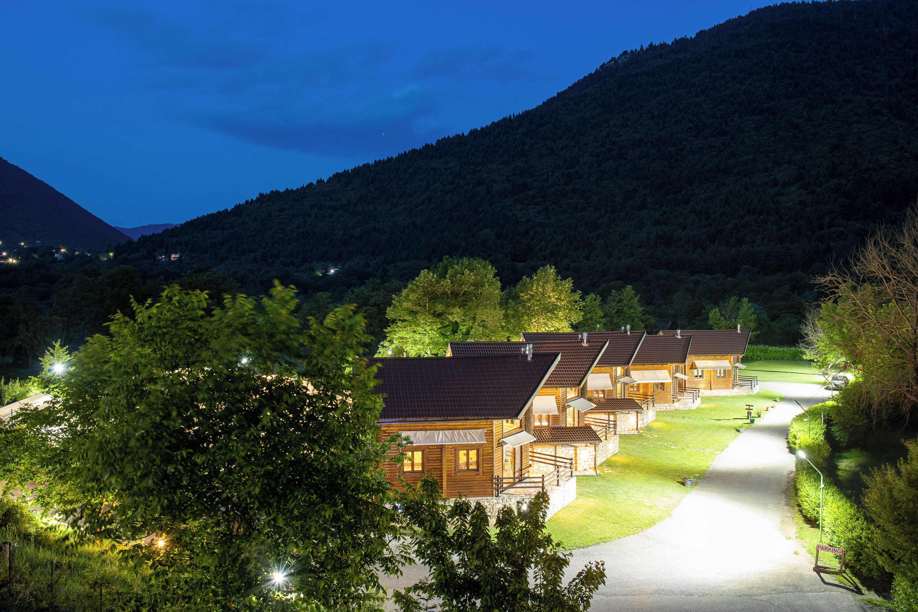 Une rangée de chalets en bois, avec une allée pavée et une vue sur les montagnes en arrière-plan.
