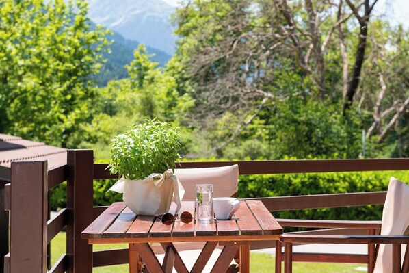 Una mesa de madera con una planta en maceta, un vaso de agua y unas gafas de sol.