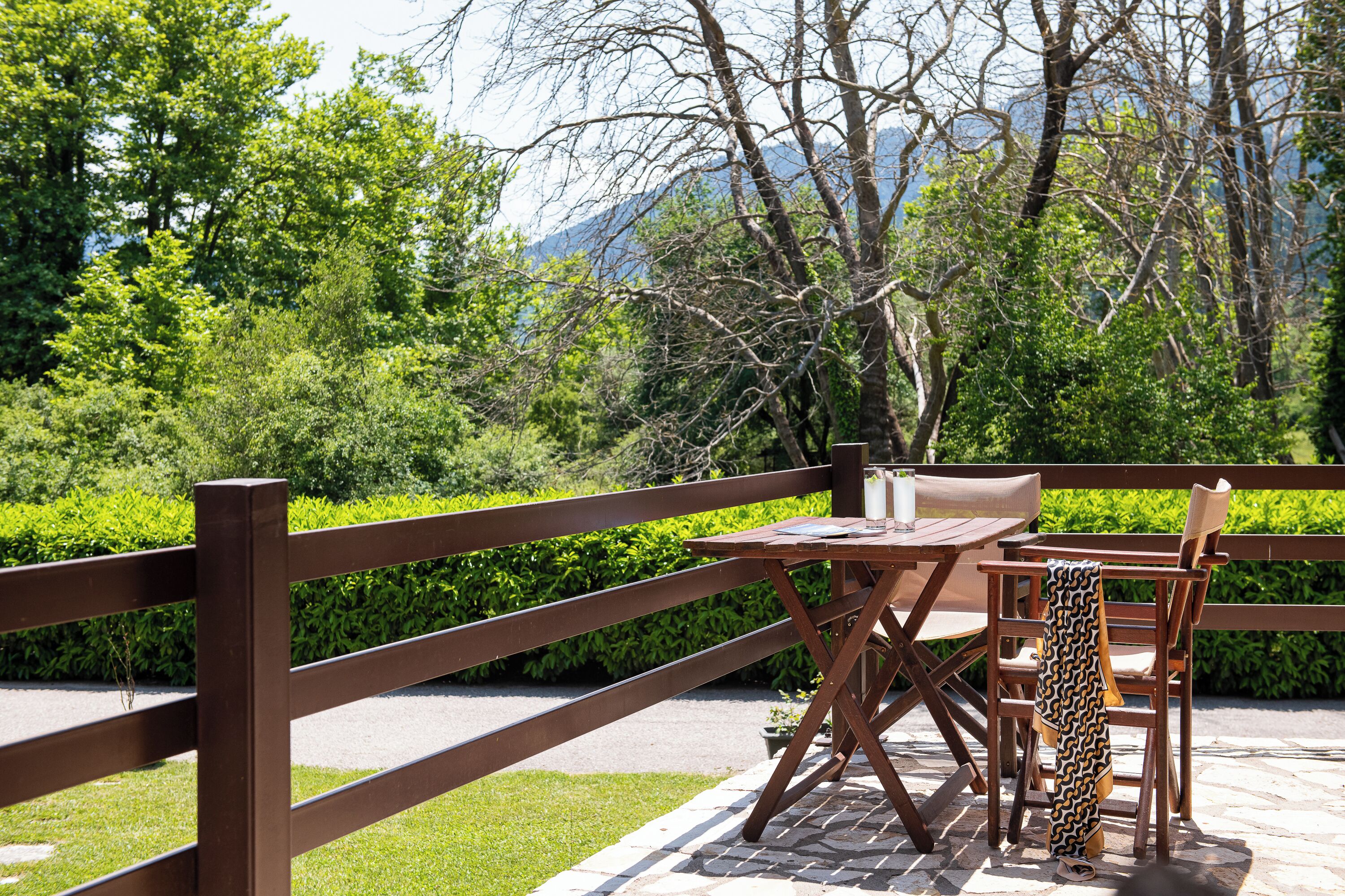 An outdoor seating area with a table and chairs, surrounded by a wooden fence and lush greenery.