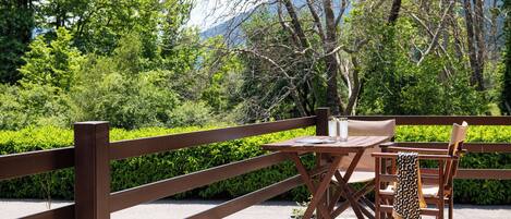 An outdoor seating area with a table and chairs, surrounded by a wooden fence and lush greenery.