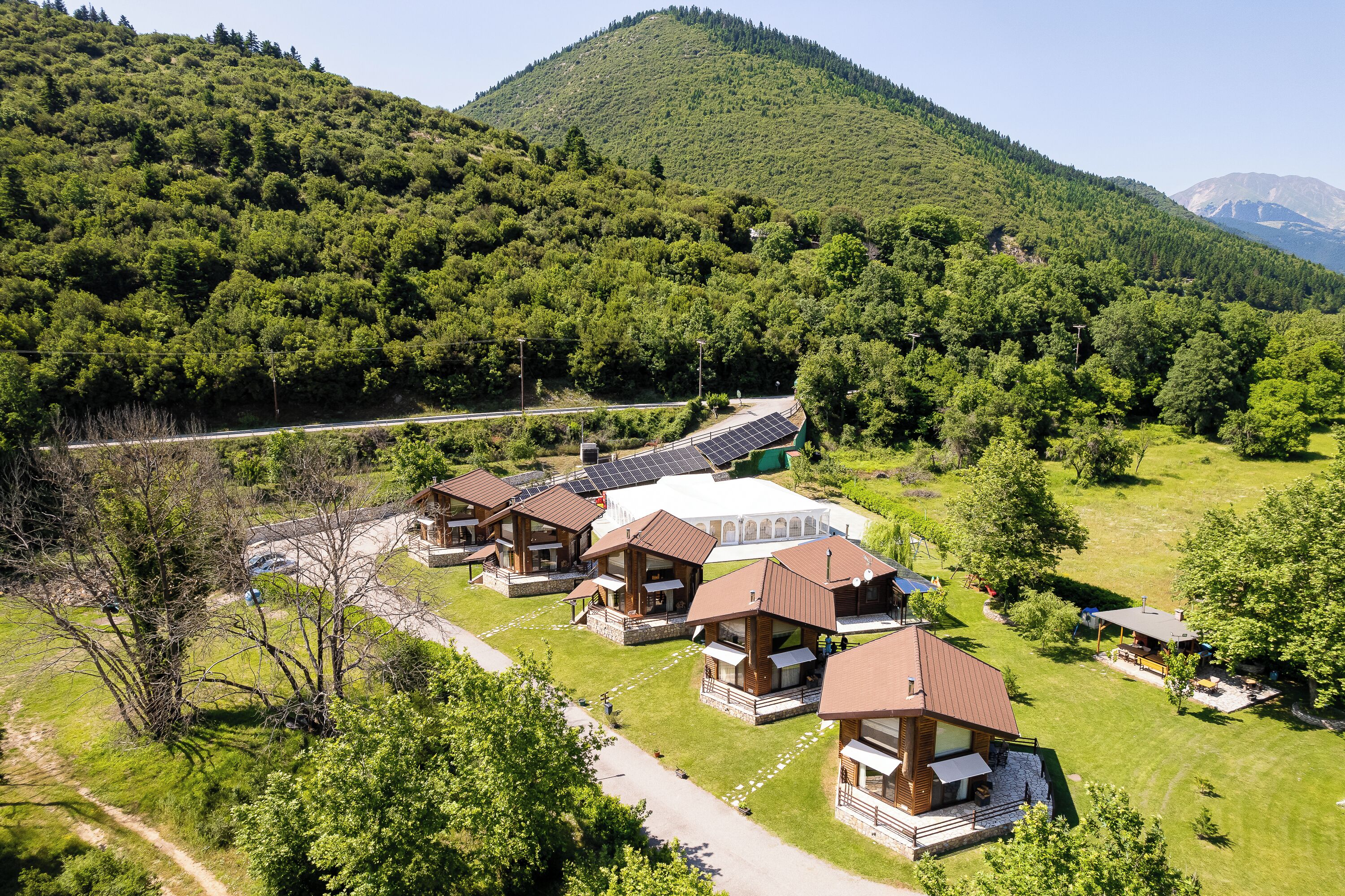 A resort with multiple cabins, a central building, and a mountainous backdrop.