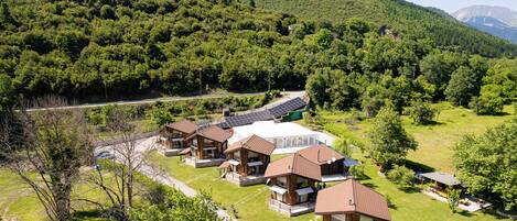 A resort with multiple cabins, a central building, and a mountainous backdrop.