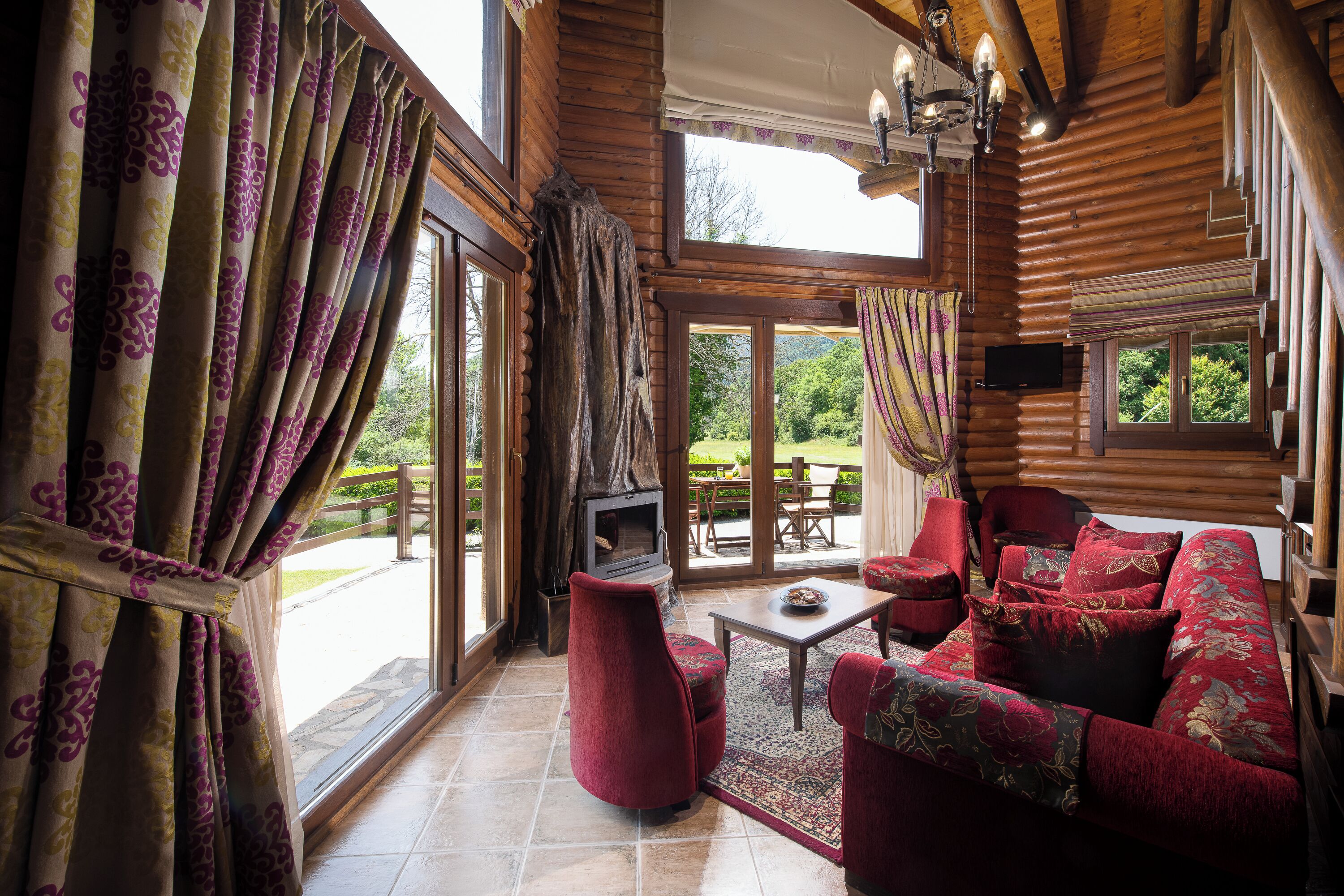 A log cabin interior with a sofa, chairs, a TV, and a fireplace.