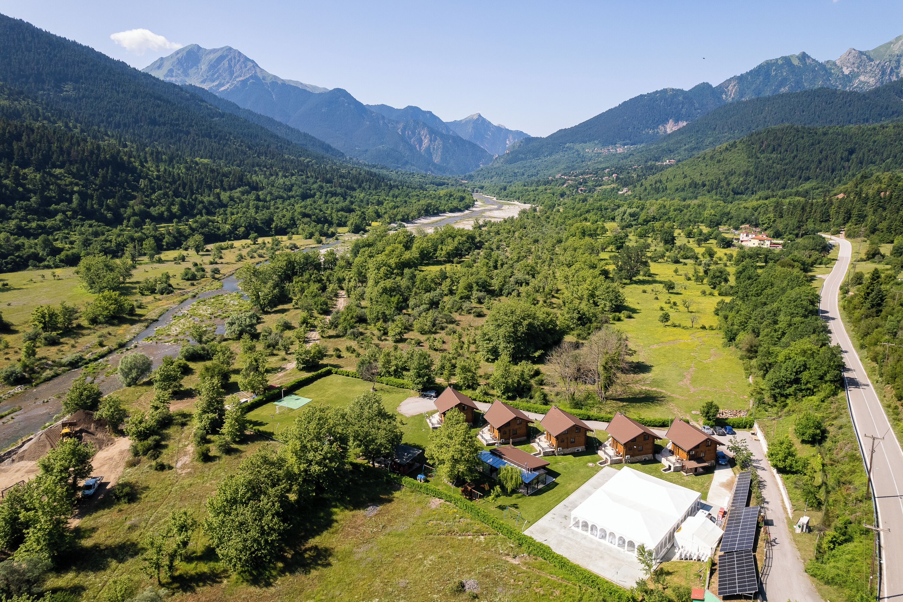 A rural area with houses, a road, and mountains in the background.